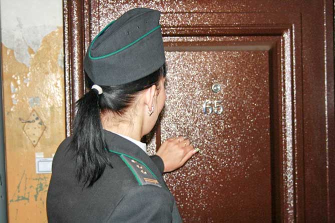 сотрудник УФССП стучится в дверь квартиры