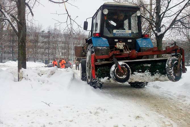 трактор чистит снег на внутриквартальной дороге