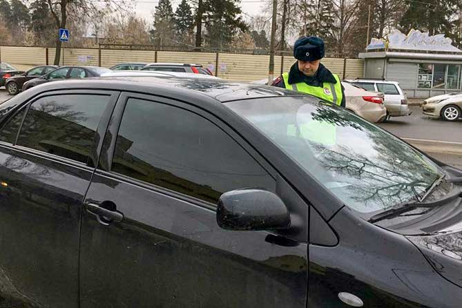 полицейский проверяет тонировку стекл автомобиля