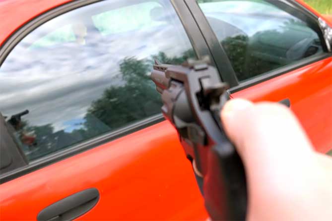 стреляет из пистолетва в автомобиль
