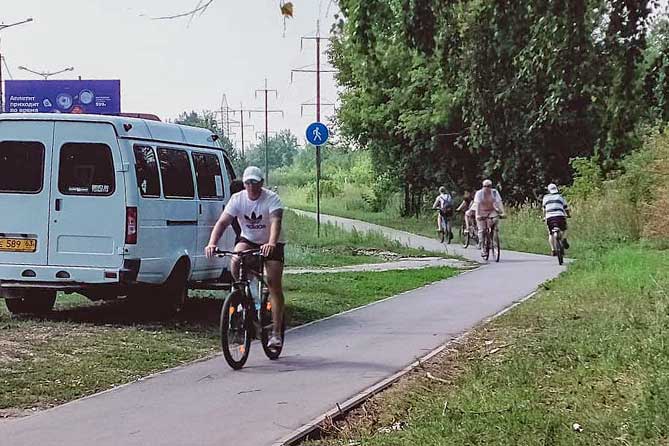 велосипедисты едут по велодорожке вдоль улицы Родины