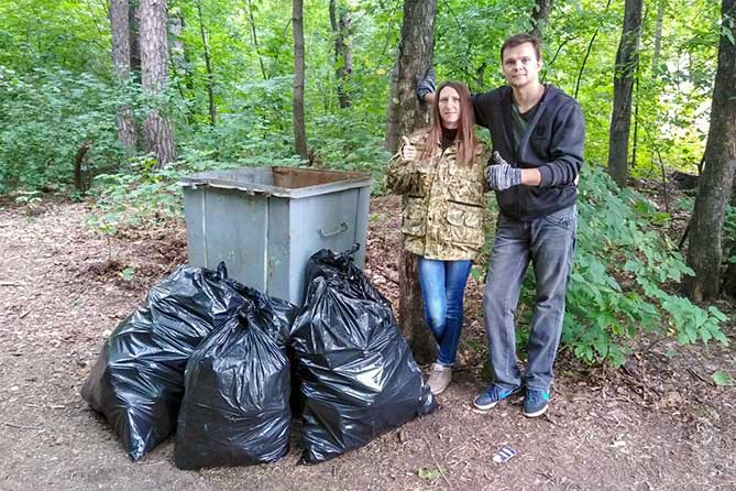 женщина и мужчина возле контейнера в лесу с мешками мусора