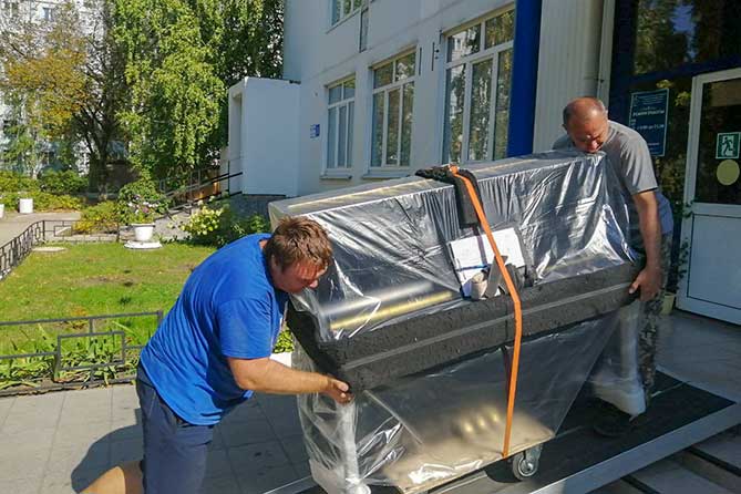 мужчины заносят новое пианино в здание ДШИ "Форте"