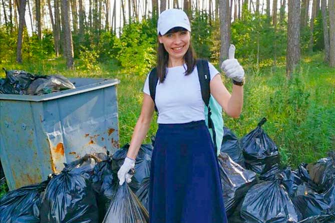 девушка в лесу с собранным мусор в мешках