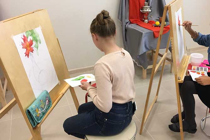 девочка рисует картину на мольберте