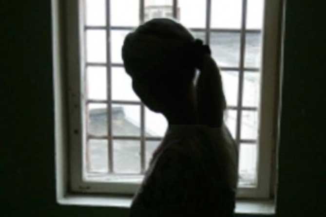 женщина стоит возле окна с решеткой