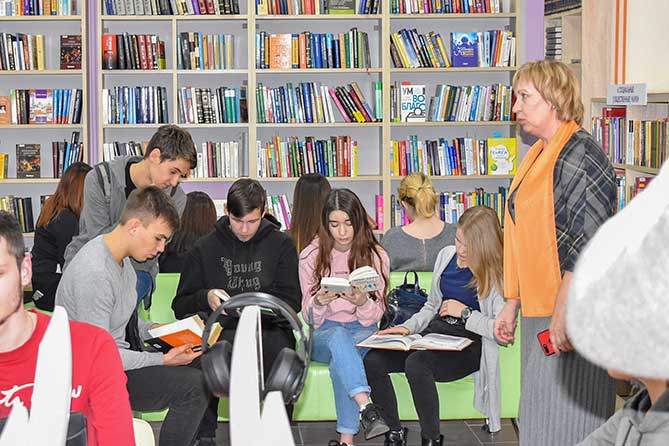 юноши и девушки читают книги в библиотеке
