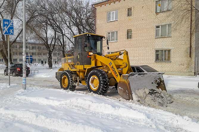 трактор чистит снег возле дома