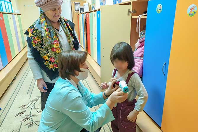 в детсаду медсестра измеряет температуру тела ребенка