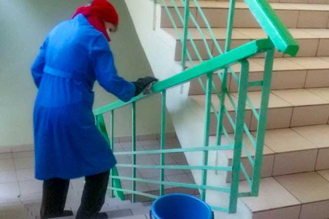женщина вытирает перила лестницы в детском саду