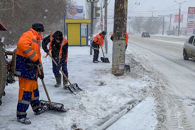 дворники чистят снег на остановке на Автозаводском шоссе