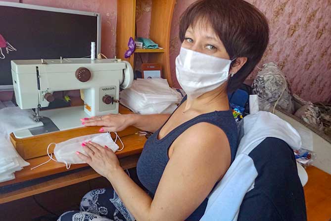женщина шьет на швейной машинке медицинские маски