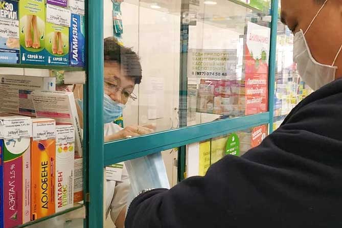 мужчина покупает защитные маски в аптеке