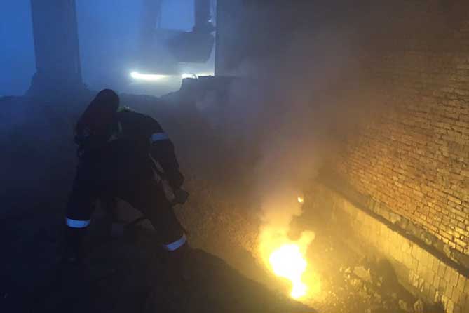 пожарный и трактор засыпают огонь песком
