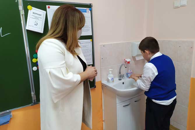 школьник моет руки в классе