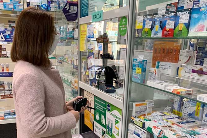 женщина покупает медикаменты в аптеке