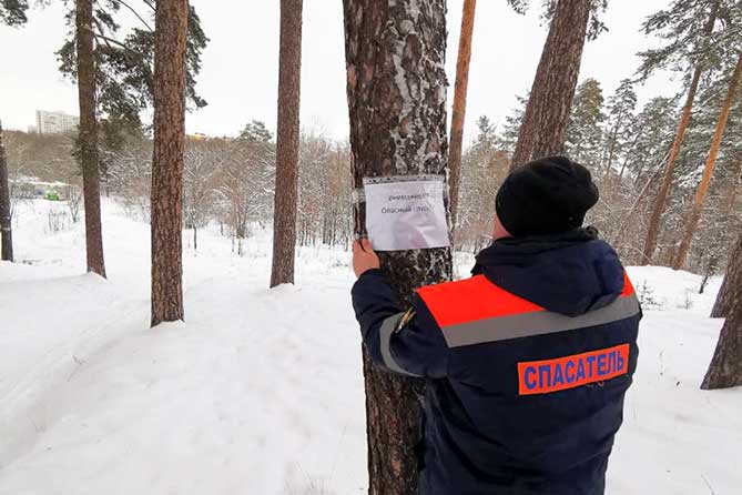 спасатель вешает предупреждающую табличку в лесу