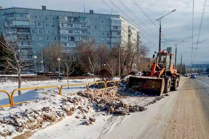 трактор убирает снег на дороге