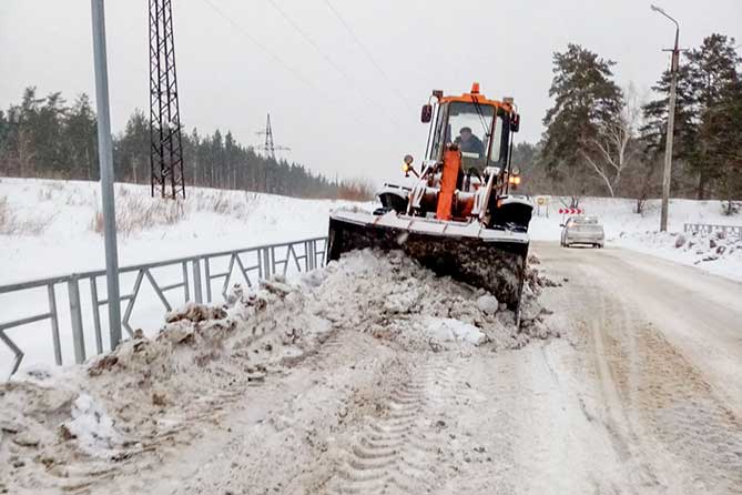 трактор чистит снег на дороге