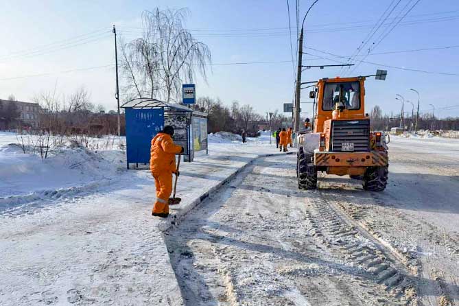 дорожный рабочий чистит снег на остановке на Степана Разина