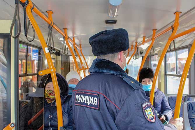 полицейский преверяет соблюдение масочного режима в автобусе