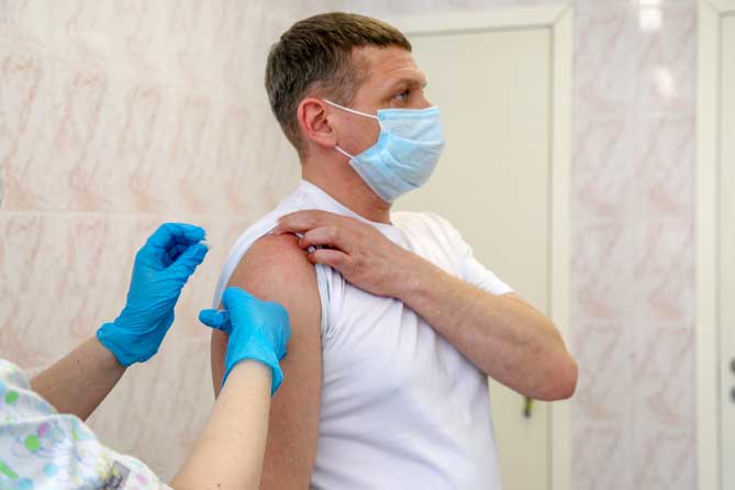 мужчине медработник делает прививку