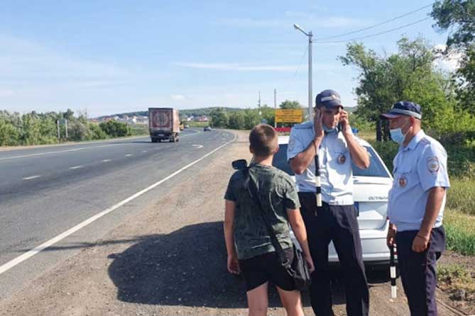полицейские стоят с мальчиком на обочине дороги