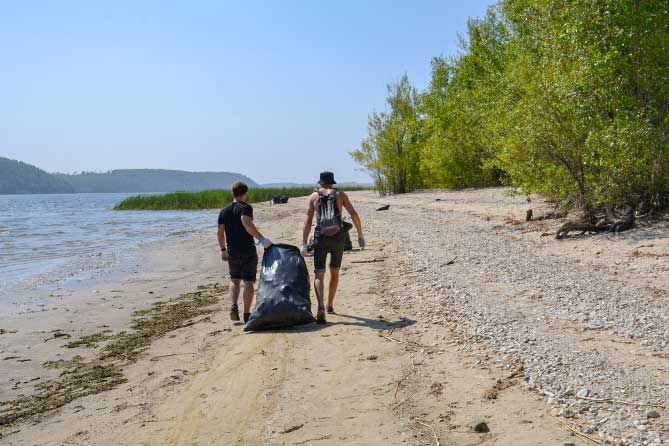 мужчины несут мешок с мусором по берегу Усы