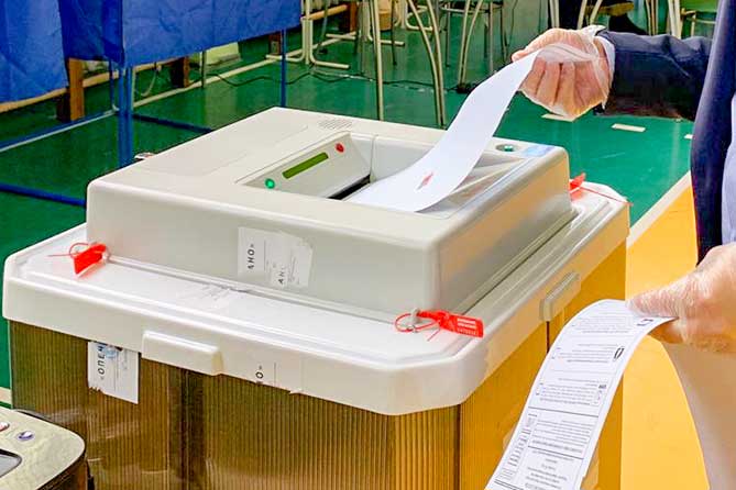 мужчина бросает бюллетень в урну для голосования