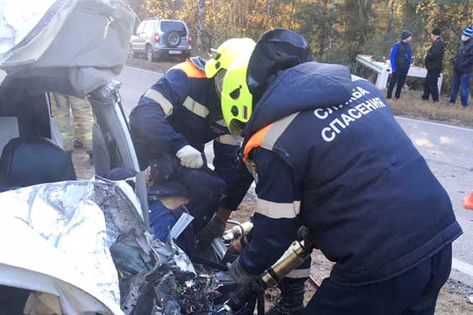 спасатели извлекают тело погибшего из автомобиля