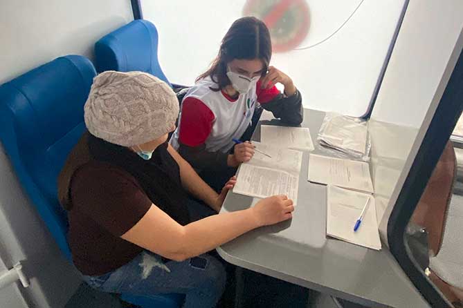 волонтер помогает заполнять анкету для вакцинации