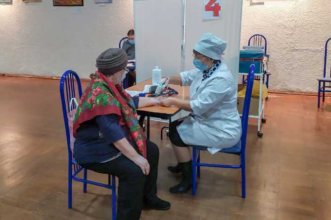 врач осматривает женщину перед вакцинацией