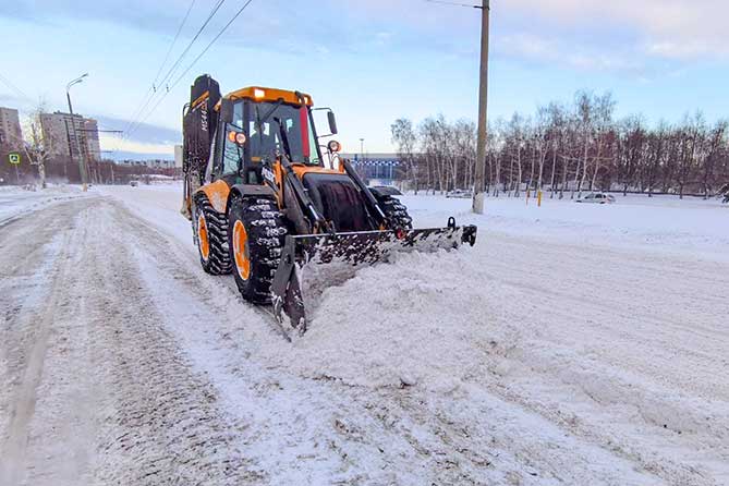 трактор чистит снег на магистрали