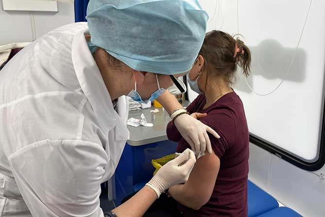 женщине делают прививку в мобильном пункте вакцинации