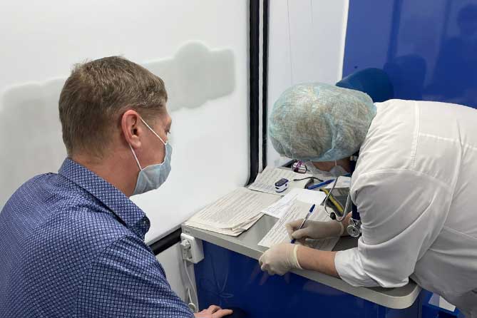 медработник заполняет анкету в мобильном пункте вакцинации