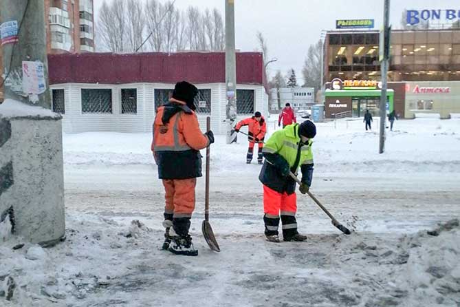 дорожные рабочие расчищают снег на пешеходном переходе