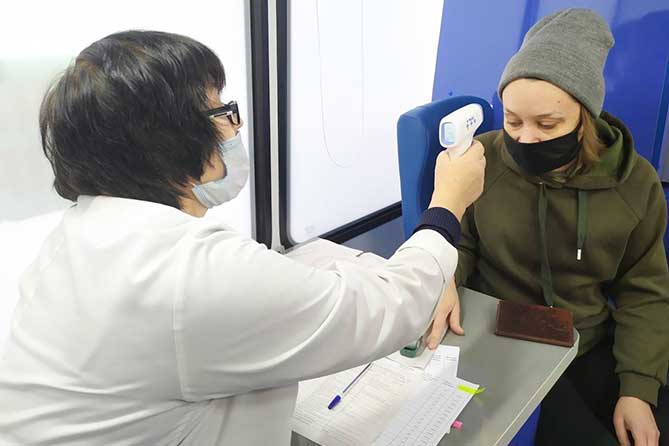 врач измеряет температуру у женщины