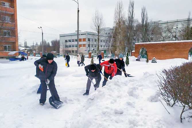 сотрудники администрации чистят снег возле пансионата для ветеранов