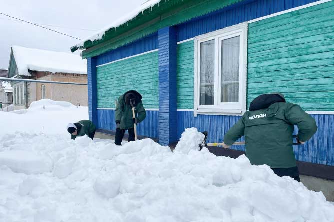 волонтеры расчищают снег у дома ветерана труда
