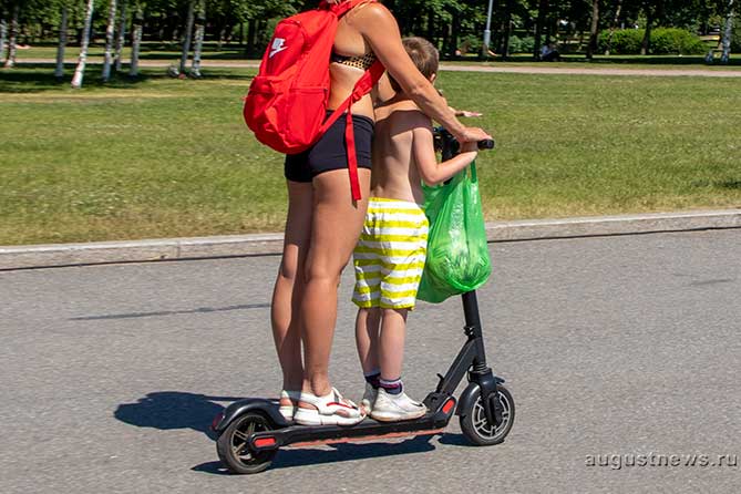 женщина едет на самокате с ребенком