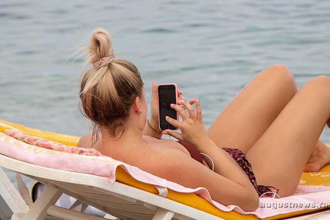 смотрит телефон на пляже