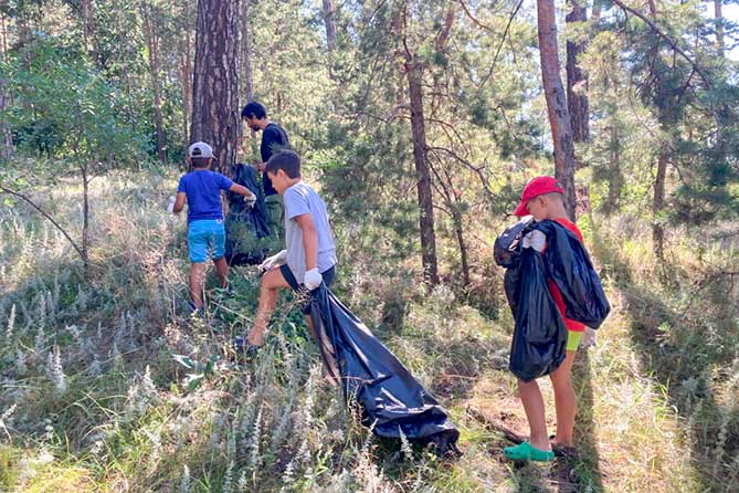 юные спортсмены собирают мусор в лесу