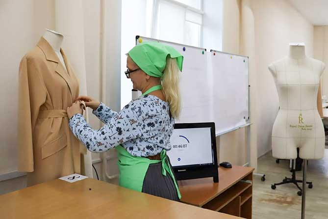 швея примеряет пальто на манекене