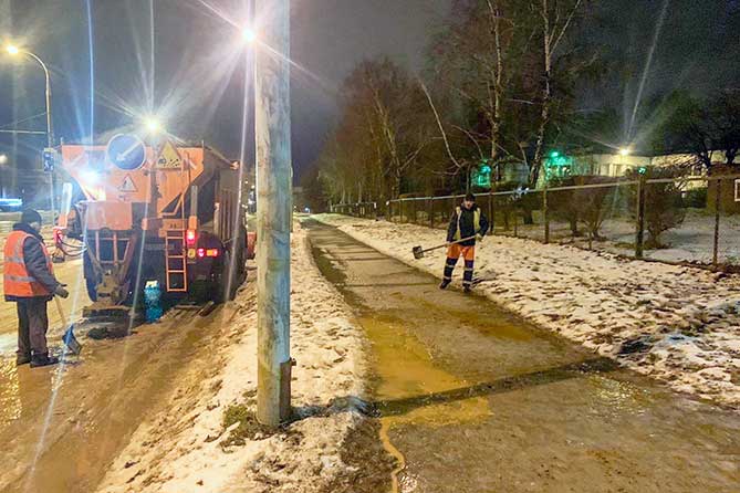 дорожная служба посыпает песком тротуар
