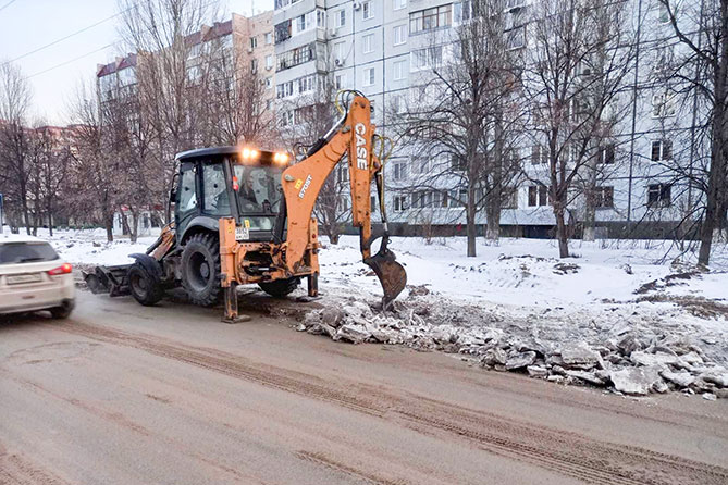 спецмашина убирает прибордюрную наледь на дороге
