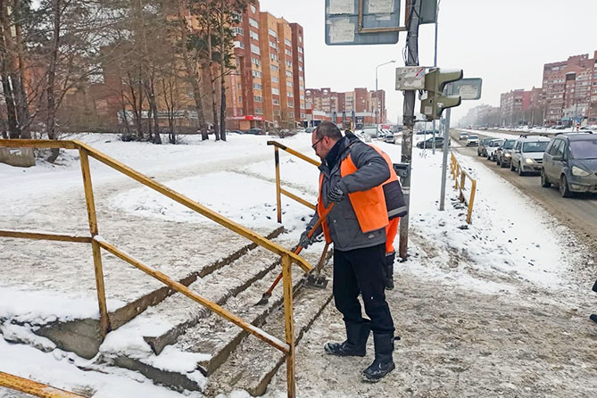 дорожный рабочий расчищает снег на лестнице