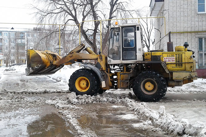 трактор чистит снег во дворе