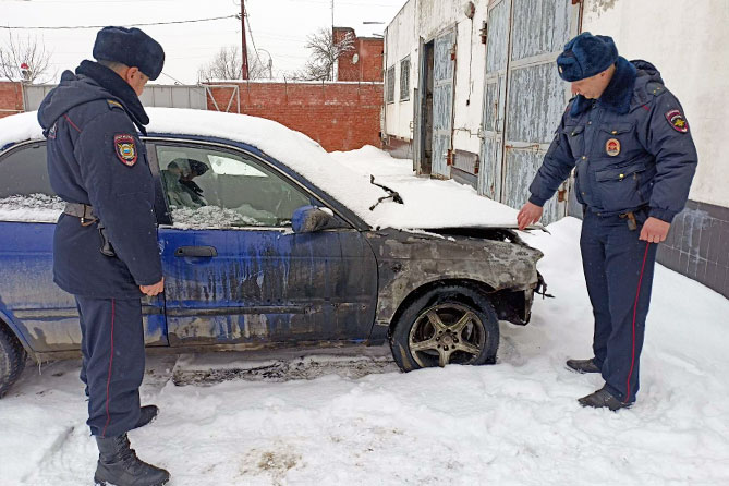 полицейские осматриваю обгоревший автомобиль