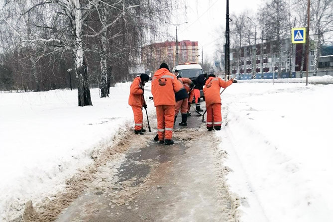 дорожные рабочие убирают наледь на тротуаре