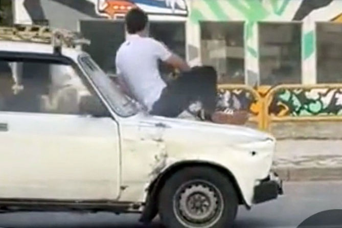 мужчина едет на капоте автомобиля